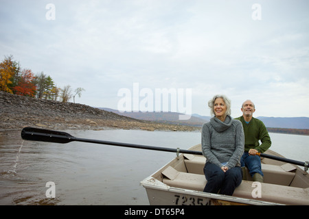 Un couple, homme et femme assis dans un bateau à rames sur l'eau une journée d'automne. Banque D'Images