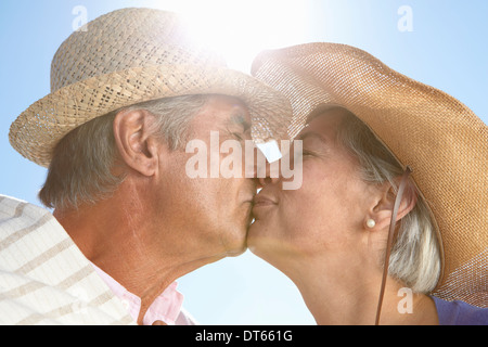 Couple wearing straw hats kissing Banque D'Images