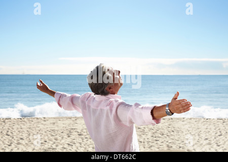 Senior man on beach avec des bras étendu