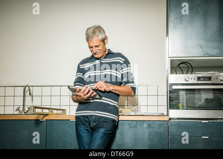 Senior man using digital tablet in kitchen Banque D'Images