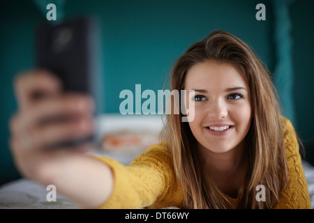 Adolescente dans la chambre en tenant un selfies Banque D'Images