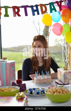 Adolescente à table avec gâteau d'anniversaire Banque D'Images