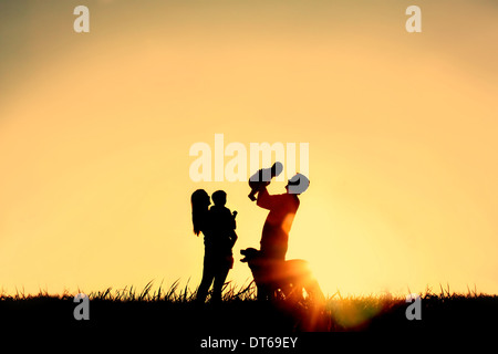 La silhouette d'une famille heureuse de quatre personnes, le père, la mère, un bébé et enfant, et de leur chien en face d'un ciel temporaire, Banque D'Images