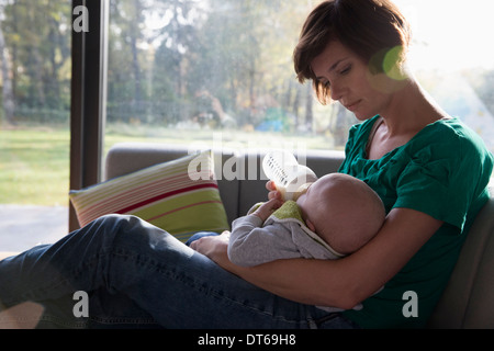 Mère de biberons baby boy sur canapé Banque D'Images