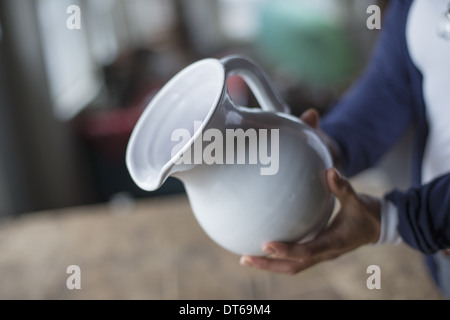 Une femme tenant une cruche poterie blanche dans un ancien magasin de meubles et de marchandises. Banque D'Images