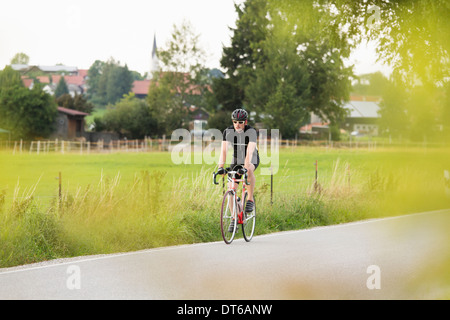 Mâle mature à vélo sur route de campagne Banque D'Images