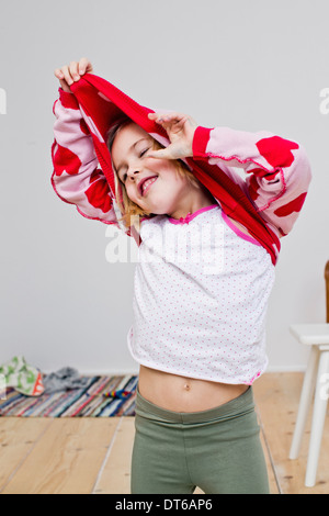 Studio shot of girl pulling off red heart sweater Banque D'Images