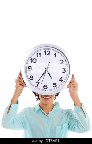 Hispanic business woman looking at camera et se cacher derrière grosse horloge sur fond blanc Banque D'Images