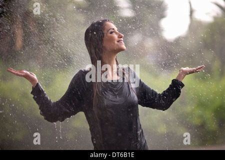 Jeune femme au soleil avec les bras ouverts dans rainy park Banque D'Images