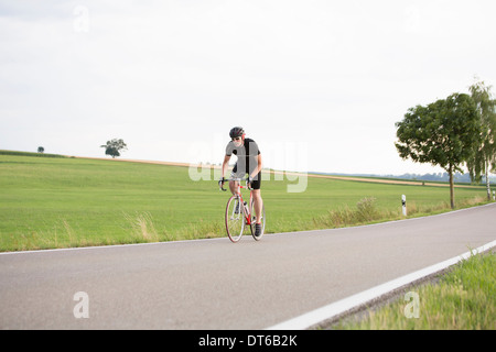Homme mûr à vélo sur route de campagne Banque D'Images