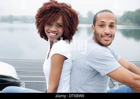 Portrait of young couple smiling, dos à dos Banque D'Images