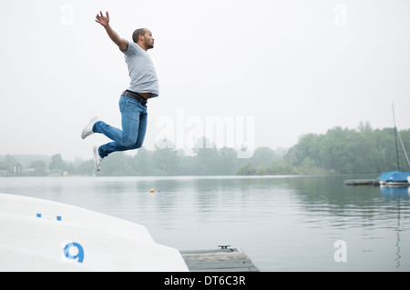 Jeune homme de sauter dans le lac Banque D'Images