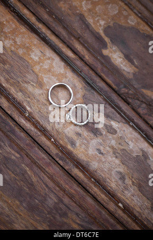 Anneaux de mariage de platine . Deux joints toriques usés sur une surface en bois coloré frotté. Banque D'Images