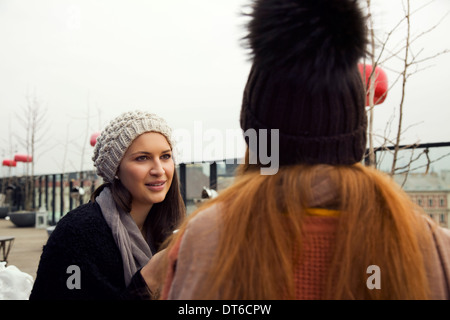 Deux jeunes femmes adultes chatter sur toit-terrasse Banque D'Images