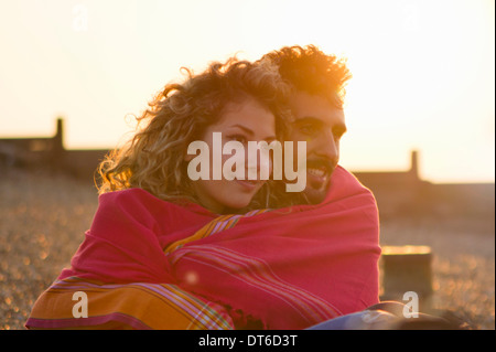 Jeune couple wrapped in towel on beach Banque D'Images