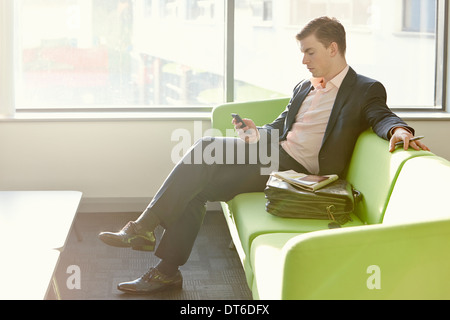 Businessman in departure lounge using cell phone Banque D'Images