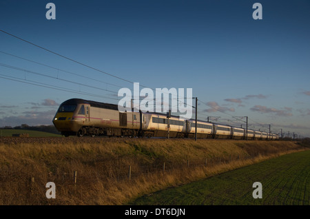 Un service de trains de la côte est les captures les derniers rayons du soir coucher de soleil sur la campagne du Lincolnshire à Hougham Without. Banque D'Images