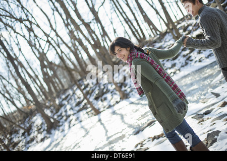 Un couple main dans la main, sur un chemin enneigé à travers les bois. Banque D'Images