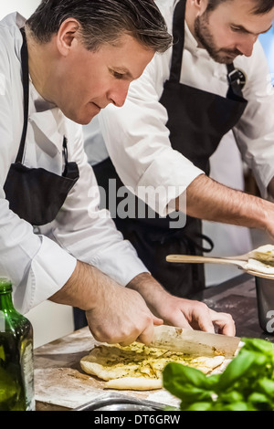 Chef slicing pizza pain en cuisine commerciale Banque D'Images