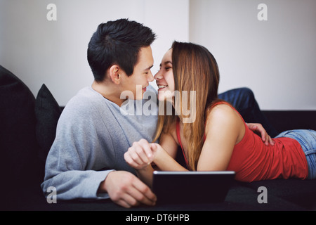 Couple romantique sur la table les uns les autres avec des tablettes numériques. Jeune couple amoureux sur le point de baiser les uns les autres. Banque D'Images