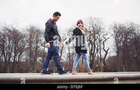 Low angle view of beau jeune homme avec sa petite amie à marcher ensemble main dans la main dans le parc. Mixed Race woman. Banque D'Images