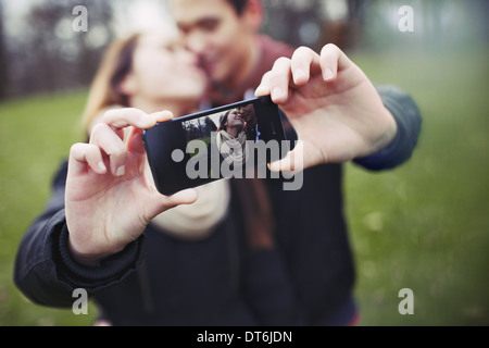 Teenage romantique couple taking self portrait with cell phone au parc. Jeune homme et femme dans l'amour. Banque D'Images