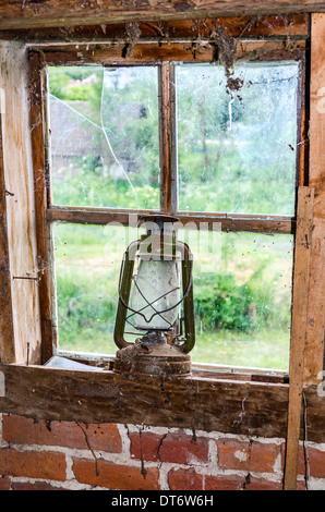 Lampe à pétrole ancienne sur un rebord de fenêtre cassée Banque D'Images