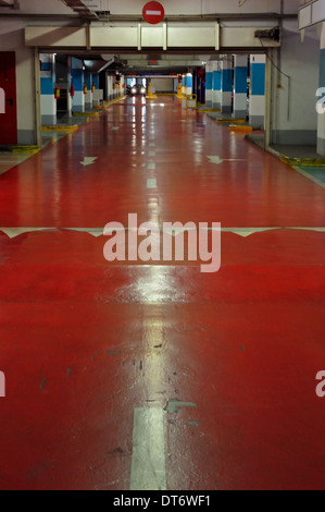 Underground parking à étages de l'intérieur. Allée rouge et voiture. Banque D'Images