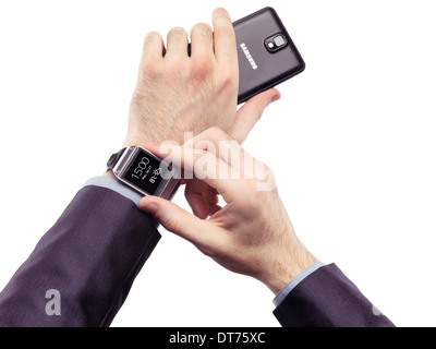 Mains d'une personne qui porte Samsung Galaxy Gear watch et la tenue d'un smartphone isolé sur fond blanc Banque D'Images