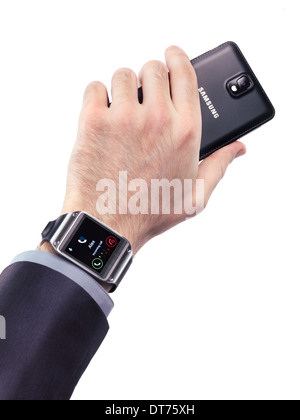 Man main avec Samsung Galaxy Gear smartwatch et un smartphone isolé sur fond blanc Banque D'Images