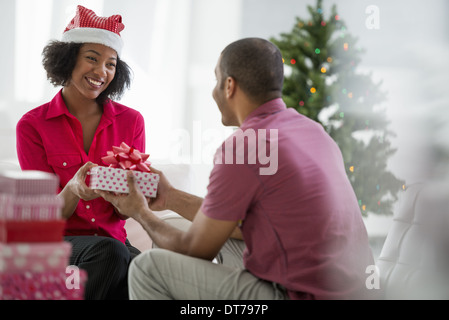 Une femme portant un Père Noël rouge et blanc hat. À la maison. Décoré d'un arbre de Noël. Banque D'Images