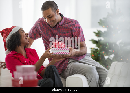 Une femme portant un Père Noël rouge et blanc hat. À la maison. Décoré d'un arbre de Noël. Banque D'Images