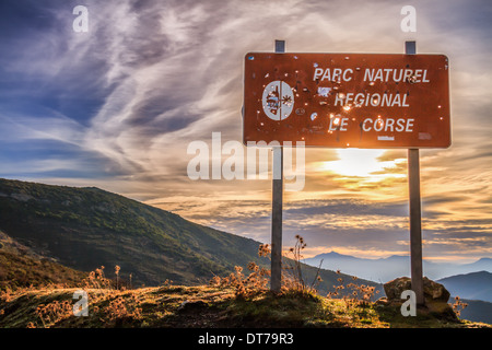Parc Naturel de Corse panneau criblé de trous de balle du chasseur contre un soleil levant Banque D'Images