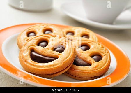 Une plaque avec un tas de smiley de biscuits et une tasse de café dans l'arrière-plan Banque D'Images