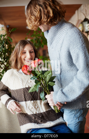 Un jeune homme donnant à bouquet de roses rouges à sa petite amie Banque D'Images