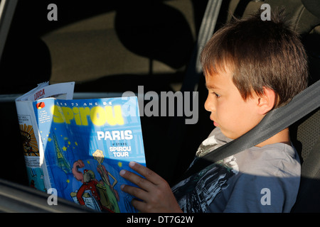 Garçon de 7 ans lit un magazine dans une voiture Banque D'Images