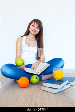 Young caucasian brunette avec Apple pour lire un livre à la maison Banque D'Images