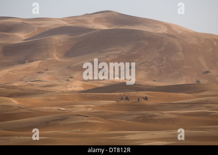 Train touristique camel au milieu de dunes au coucher du soleil dans le désert du Sahara à l'Erg Chebbi, Merzouga, Maroc Banque D'Images