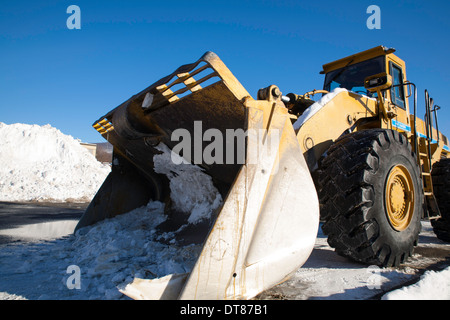 Un énorme engin de terrassement attend en Nouvelle Angleterre shopping parking de centre commercial empilées de neige récente. Banque D'Images