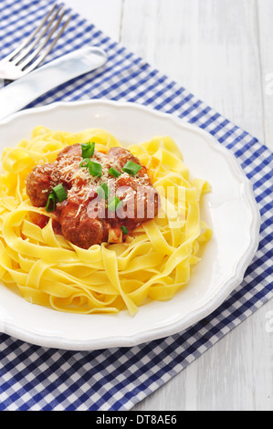 Des boulettes de viande avec des pâtes et du parmesan en plaque blanche sur fond de bois Banque D'Images