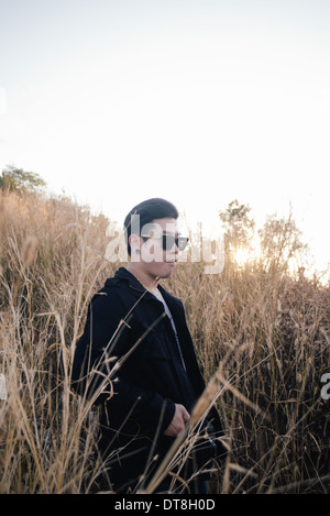 Vintage photo de jeune homme avec le lever du soleil dans le champ d'herbe matin temps Banque D'Images