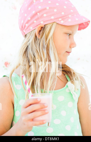 De graves à la cute young girl holding smoothie aux fruits lait en verre avec paille rayé Banque D'Images