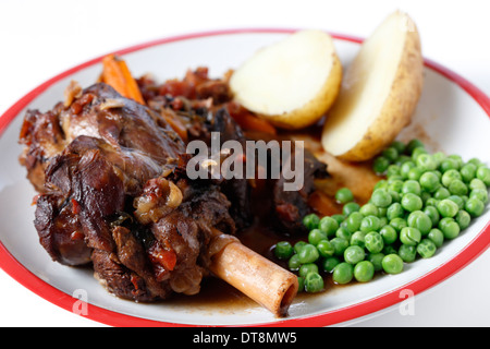 Souris d'agneau braisée avec du vin, l'oignon, l'ail, les carottes, les champignons et les herbes, servi avec des pommes de terre et les pois verts. Banque D'Images