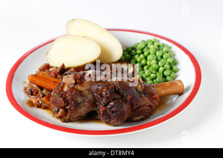 Souris d'agneau braisée avec du vin, l'oignon, l'ail, les carottes, les champignons et les herbes, servi avec des pommes de terre et les pois verts. Banque D'Images