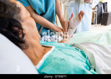 Nurse Putting Bandage sur la main du patient en position debout par médecin Banque D'Images