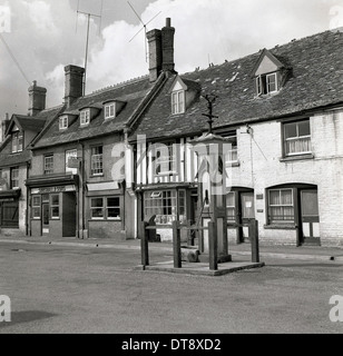 Photo historique de 1950 montrant un ancien puits d'eau et de marché au milieu d'un village-rue, en Angleterre. Banque D'Images