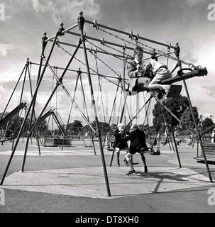 Photo historique de 1960 montrant quatre garçons de l'école une assis fluctuations de d'un terrain de jeux. Banque D'Images