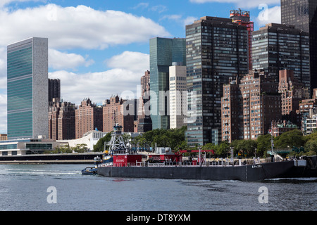 Midtown Manhattan et Tugboat Pushing Barge l'East River, New York City, USA Banque D'Images