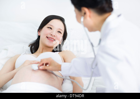 Doctor examining pregnant woman at home Banque D'Images