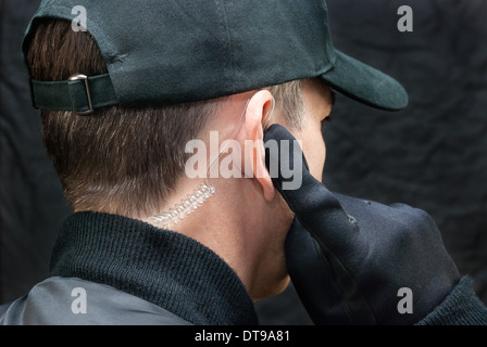 Close-up d'un garde de sécurité à l'écoute de son écouteur. Tourné à partir de, sur l'épaule. Banque D'Images